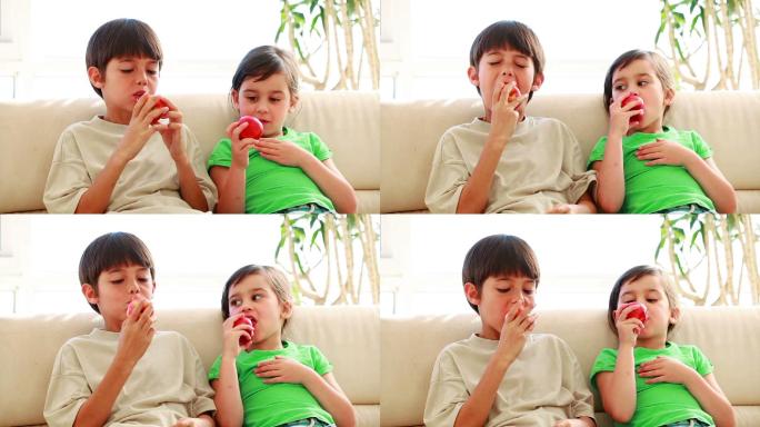 安静的兄弟姐妹在客厅里吃红苹果