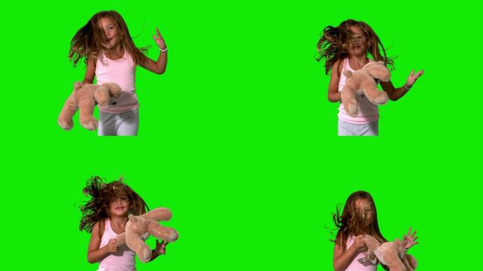 小女孩跳起来和旋转与泰迪在绿色屏幕慢动作
