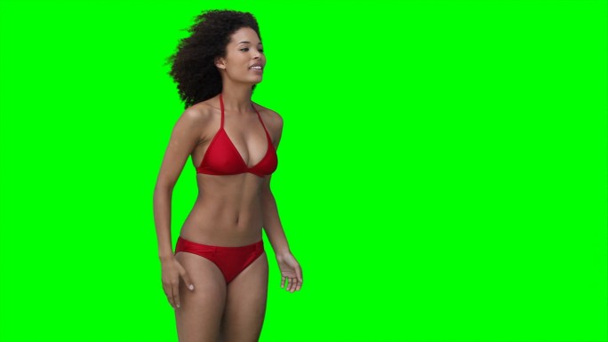 一个女人把一个沙滩球从屏幕上多次抛向绿色的背景