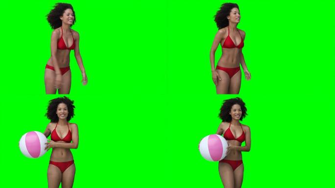一个女人把一个沙滩球从屏幕上多次抛向绿色的背景