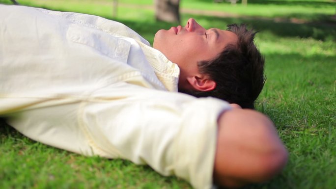 一个快乐的人躺在公园的草地上