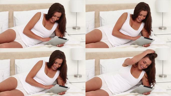 微笑的女人在她的卧室里用电子书
