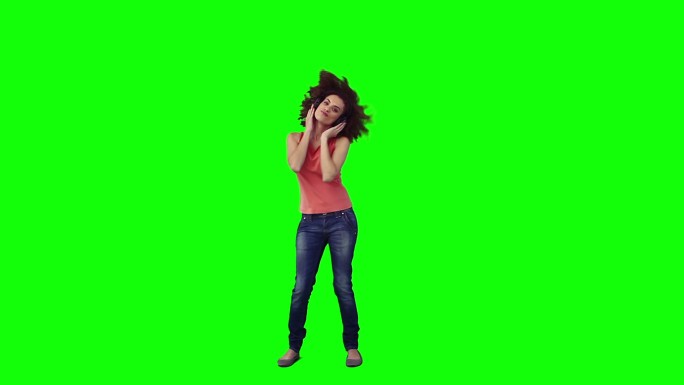 一个戴着耳机的女人在绿色背景下跳舞