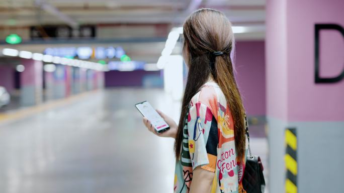 4K年轻女性在地下停车场使用手机打车软件