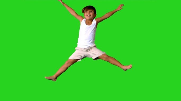 快乐的小男孩在绿色屏幕上跳跃的慢镜头