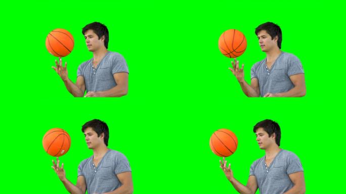一名男子在绿色背景下用手指旋转篮球