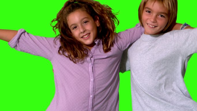 哥哥和妹妹跳进同一个镜头，并在一个绿色屏幕上以慢镜头相拥