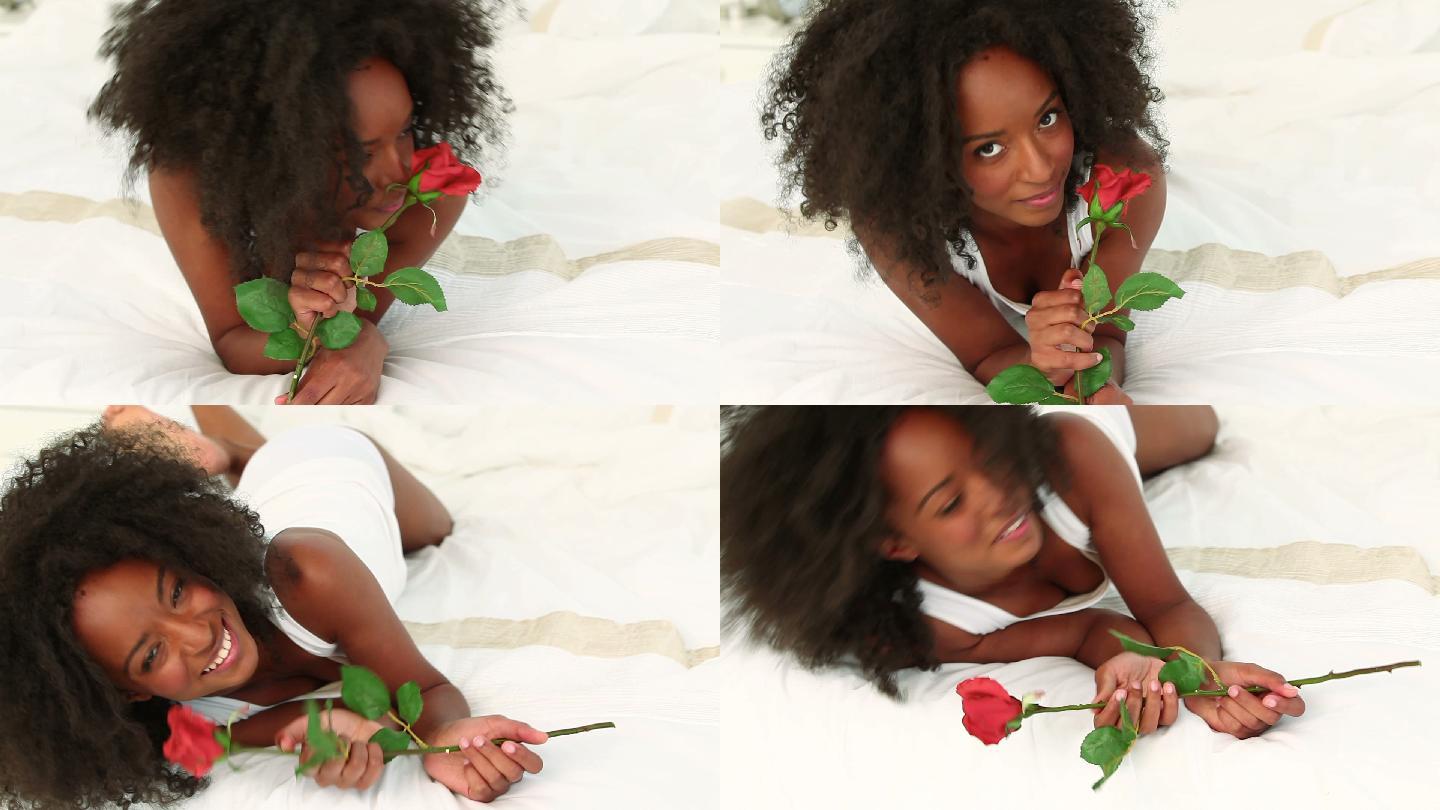 黑头发的女人在她的床上拿着一朵玫瑰