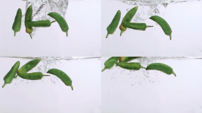 四个辣椒以超慢的动作落在白色的背景下
