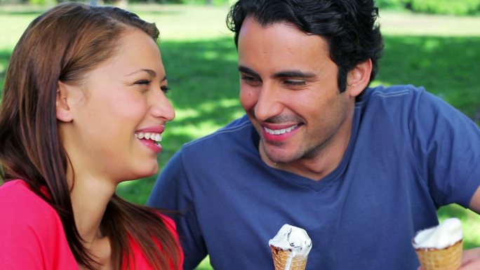 一对微笑的情侣在公园里吃甜筒