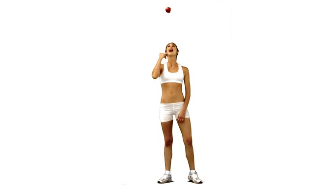 在白色的背景下，一个女人在慢镜头中接住并扔出一个苹果