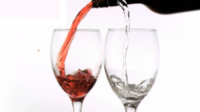 葡萄酒以超慢的动作倒在白色背景的玻璃杯中