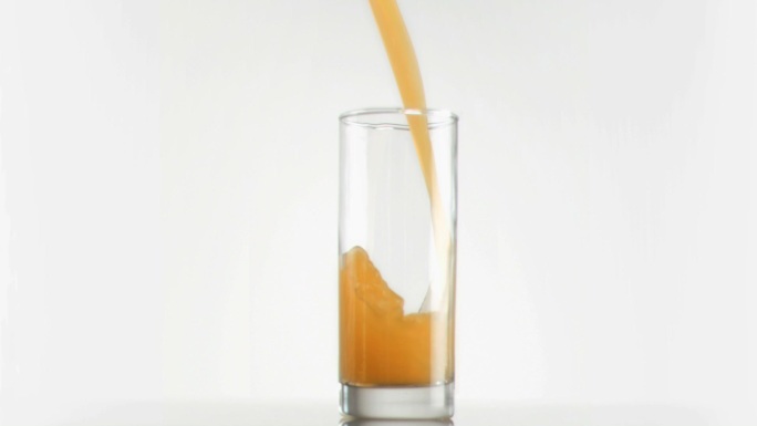 用超慢的动作将芒果汁倒入玻璃杯中