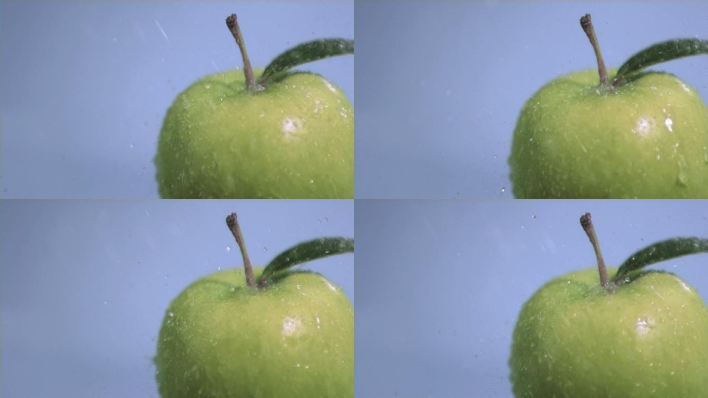 在蓝色背景下，水以超慢的动作落在苹果上