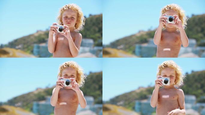 一个孩子在海滩上用数码相机拍照