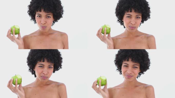 在白色背景下吃绿苹果的女人