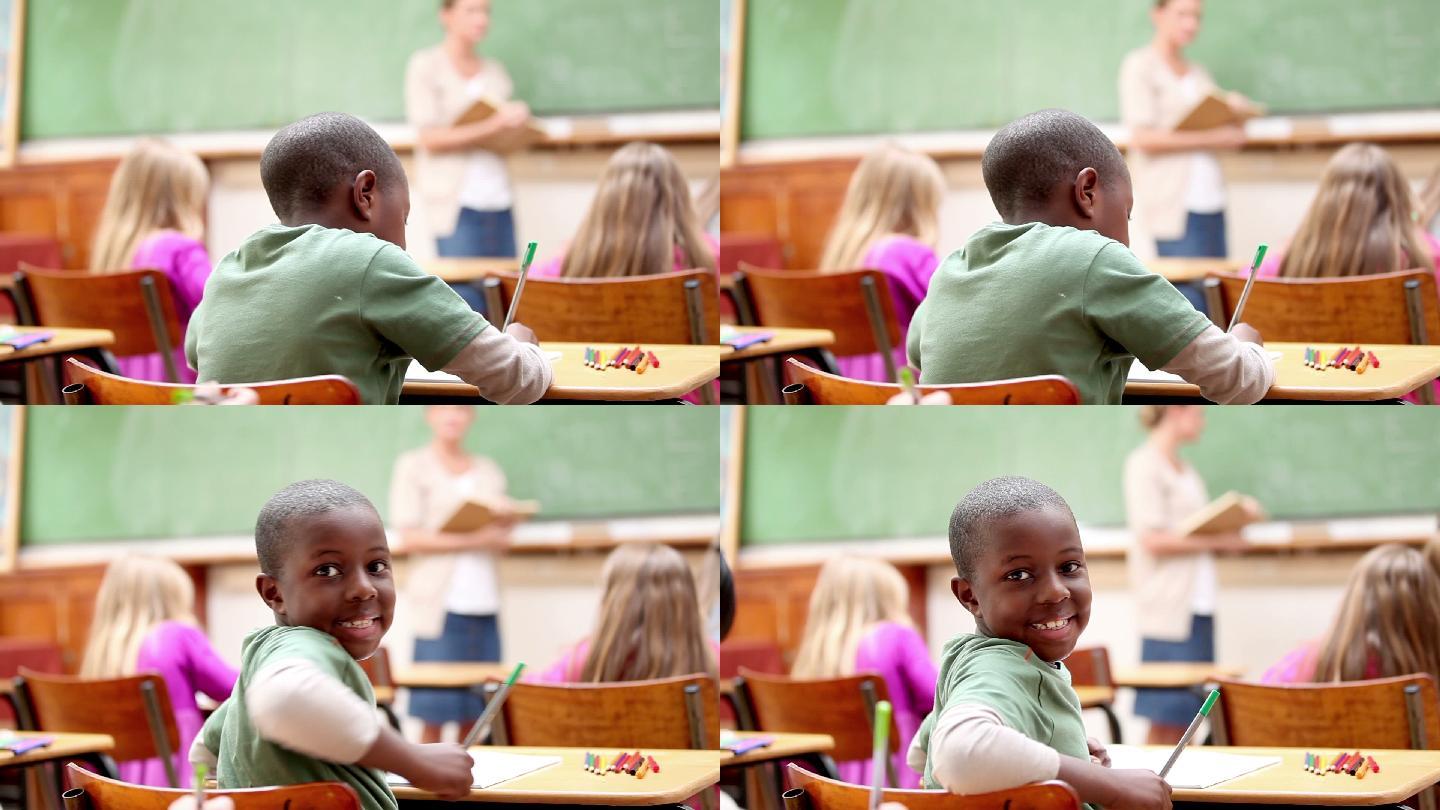 微笑的男孩在教室里工作