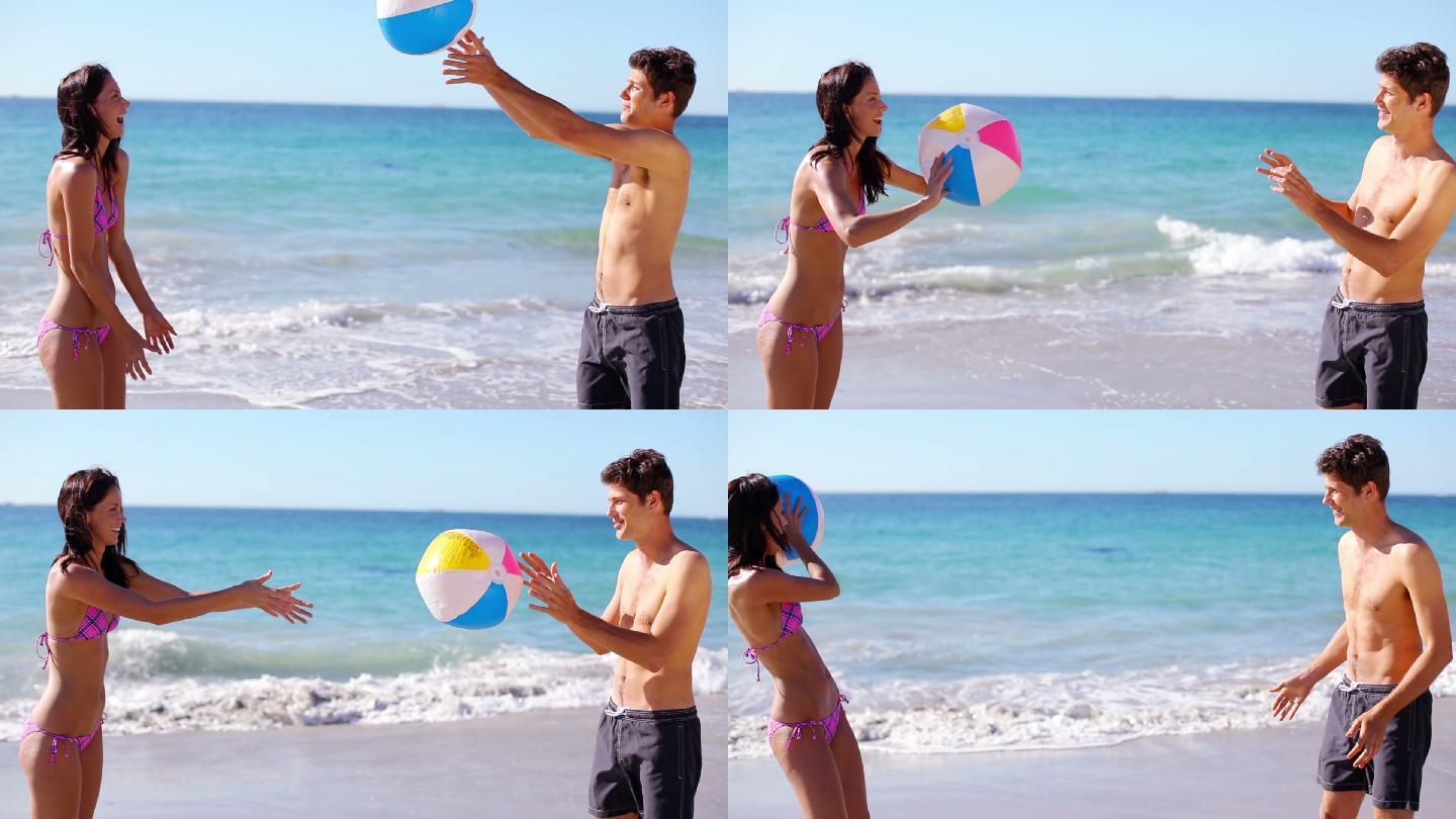 一对微笑的情侣在大海前玩沙滩球