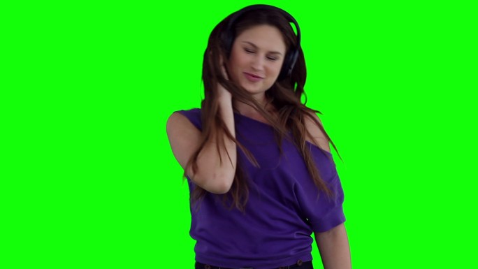 一个女人戴着耳机在绿色背景下快乐地跳舞
