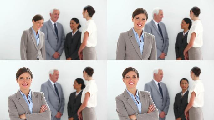 当她的同事在白色背景下交谈时，快乐的女商人在摆姿势