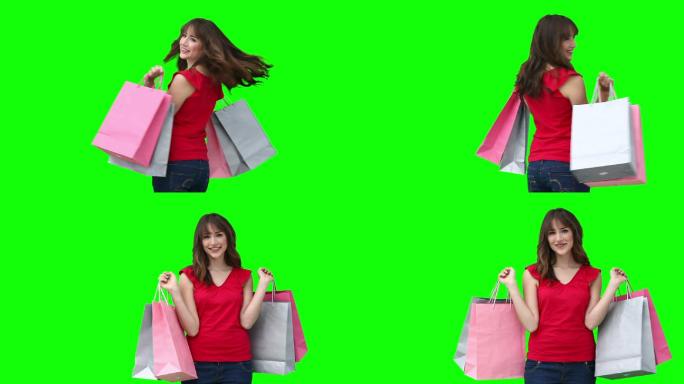 女人微笑着拿着购物袋对着绿色的背景