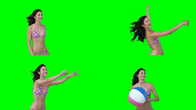 一个女人在绿色背景下击打着屏幕外的一个沙滩球