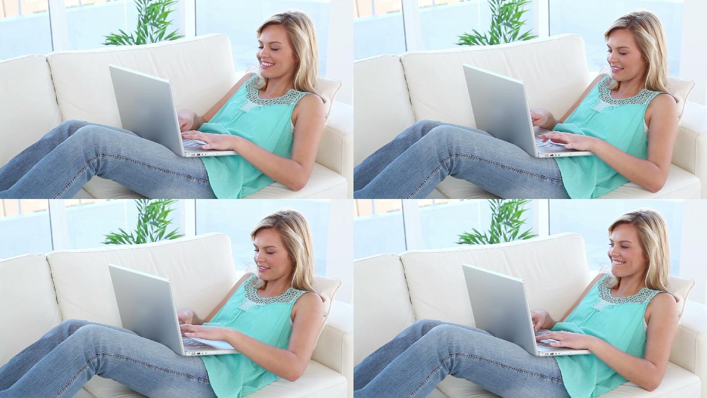 微笑的金发女人在客厅用笔记本电脑