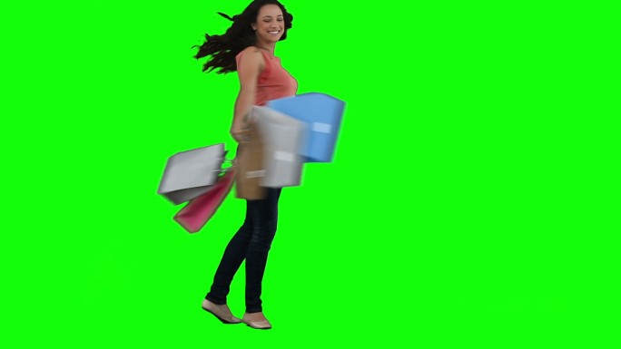 一个兴奋的女人拿着购物袋在一个绿色的背景