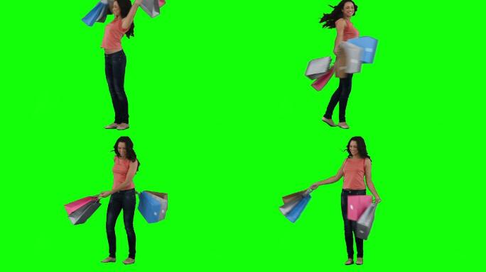 一个兴奋的女人拿着购物袋在一个绿色的背景