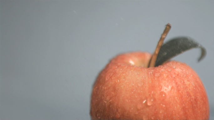 水落在红苹果上慢镜头，在灰色背景下