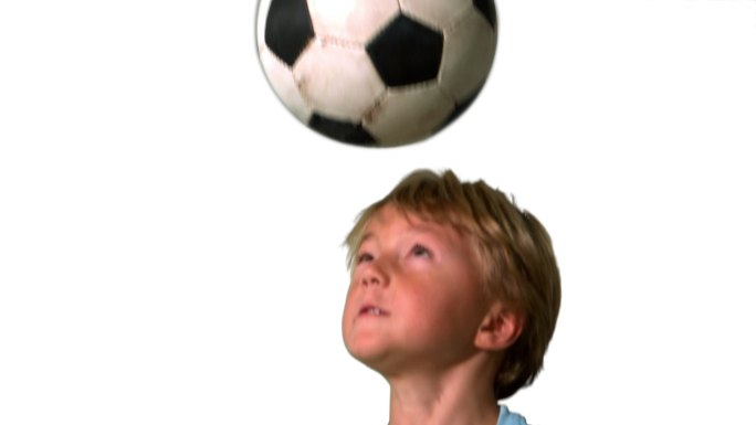 白色背景下的慢镜头里，小男孩顶着足球