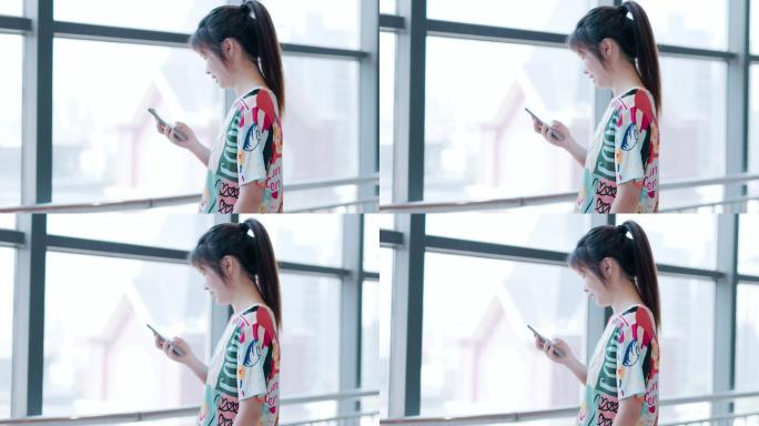 4K年轻女性在玻璃窗户旁边使用手机