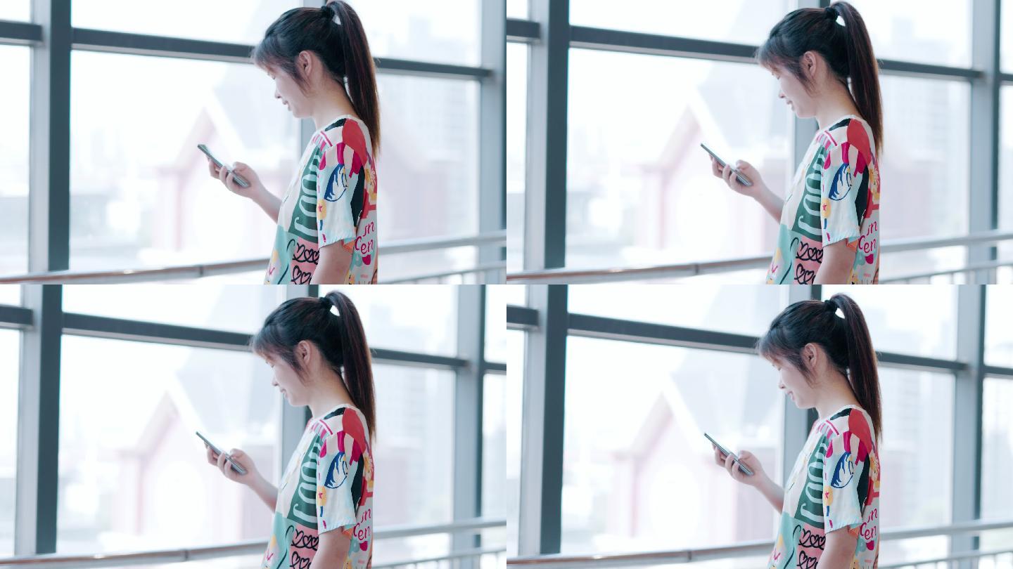 4K年轻女性在玻璃窗户旁边使用手机