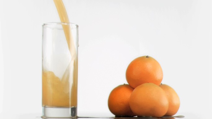 用超级慢动作将新鲜橙汁倒入大玻璃杯中