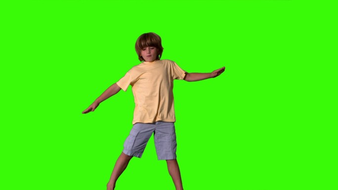小男孩伸开四肢在绿色屏幕上跳跃的慢动作