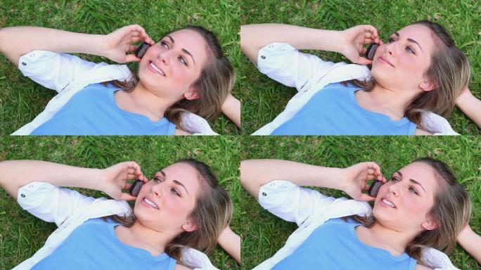 一个面带微笑的女人躺在草地上打电话
