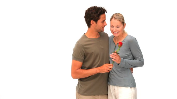 一个男人给他的妻子一朵红玫瑰孤立在白色的背景