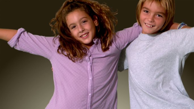 哥哥和妹妹跳进同一个镜头，拥抱在灰色背景的慢动作