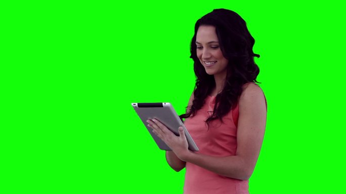 女性在看绿色背景下的摄像头前使用平板电脑