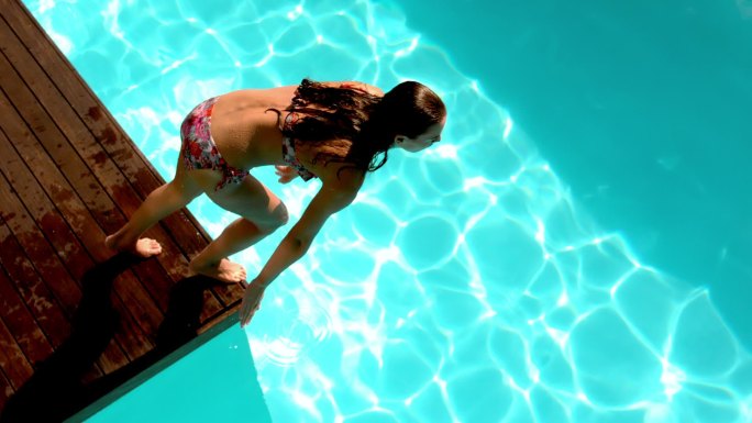 黑发女子在游泳池里慢动作跳水