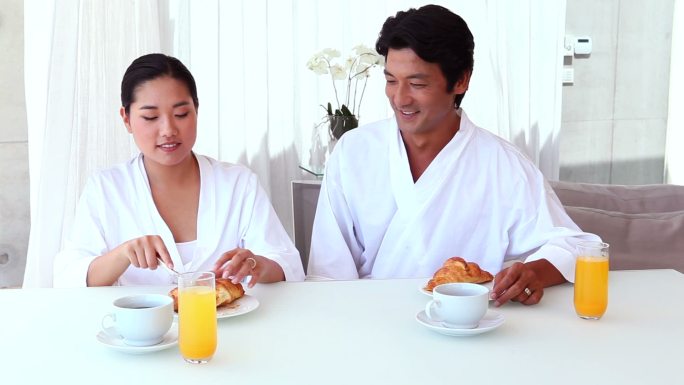 一对亚洲夫妇在客厅里一起吃早餐