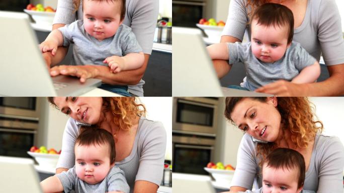 母亲坐在膝上，儿子在厨房里使用笔记本电脑