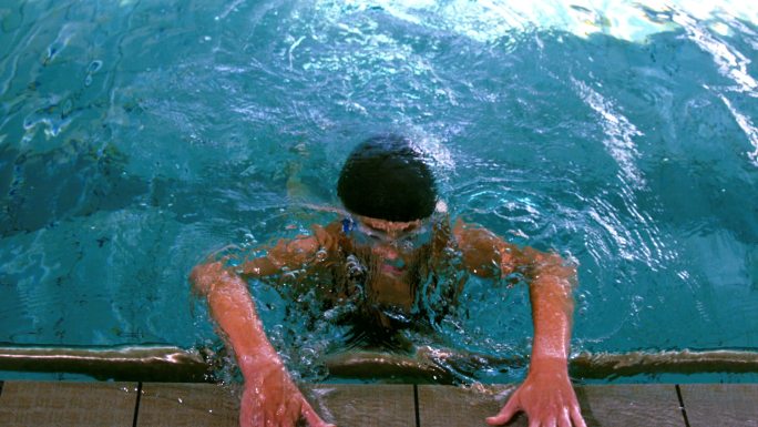 健康的游泳者从游泳池和拉动自己在缓慢的动作