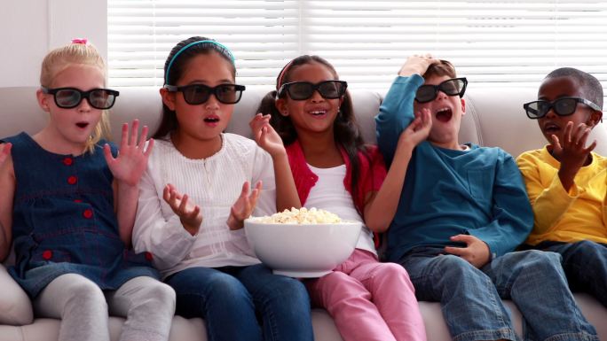 可爱的孩子们在客厅的沙发上看3d电影