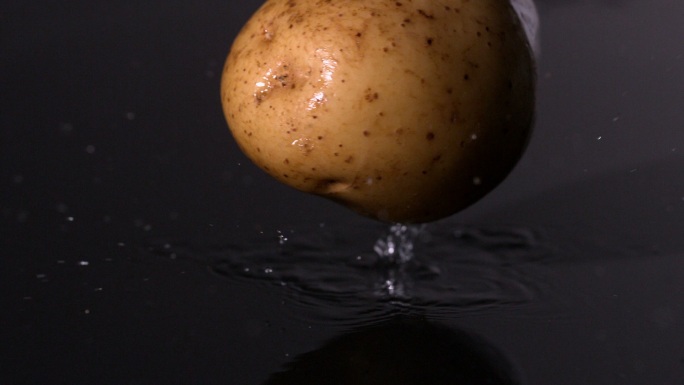 土豆落在潮湿的黑色背景慢镜头