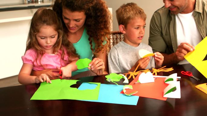 父母和孩子一起在桌子上用慢镜头画纸的形状
