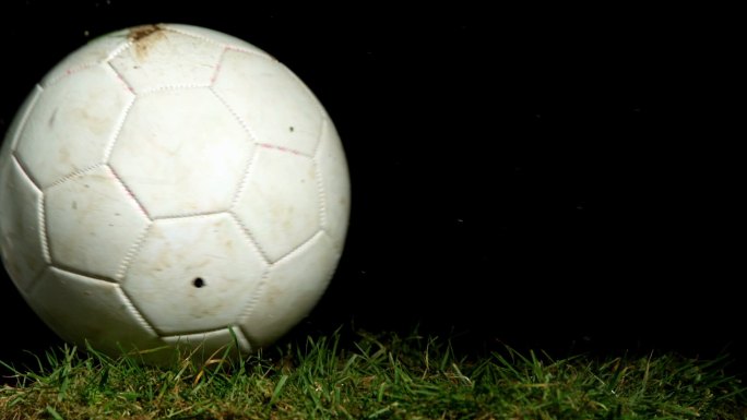 肮脏的足球在草地上慢镜头滚动