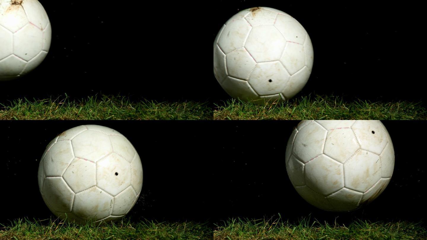 肮脏的足球在草地上慢镜头滚动