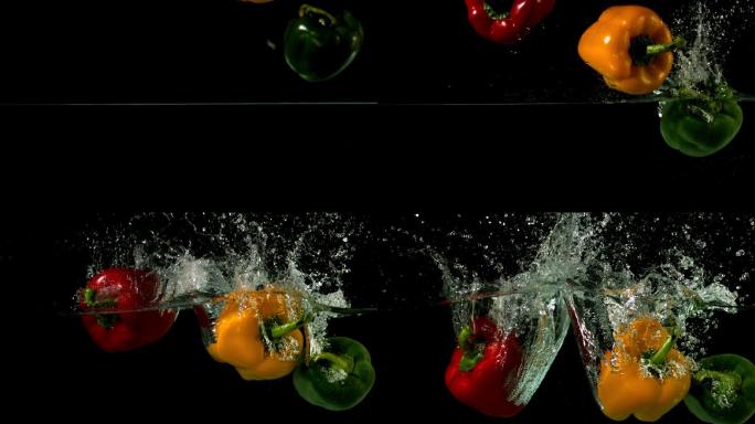 在黑色背景的慢镜头中，三个辣椒落在水中