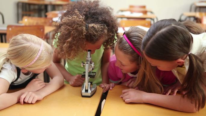 同学们在教室里透过显微镜看东西